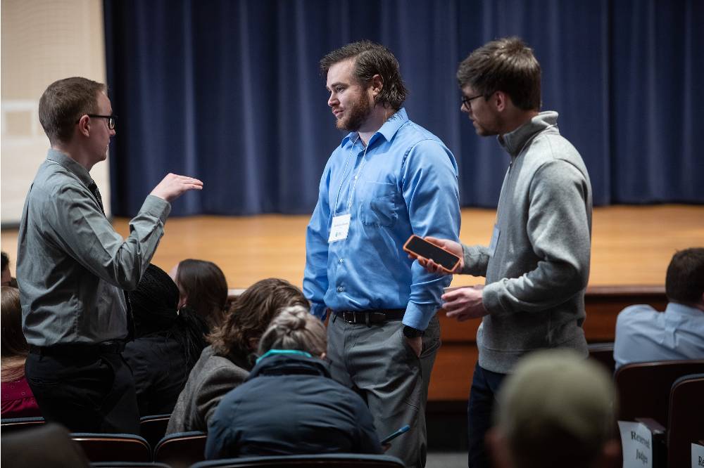 Students standing and speaking to each other in the audience
